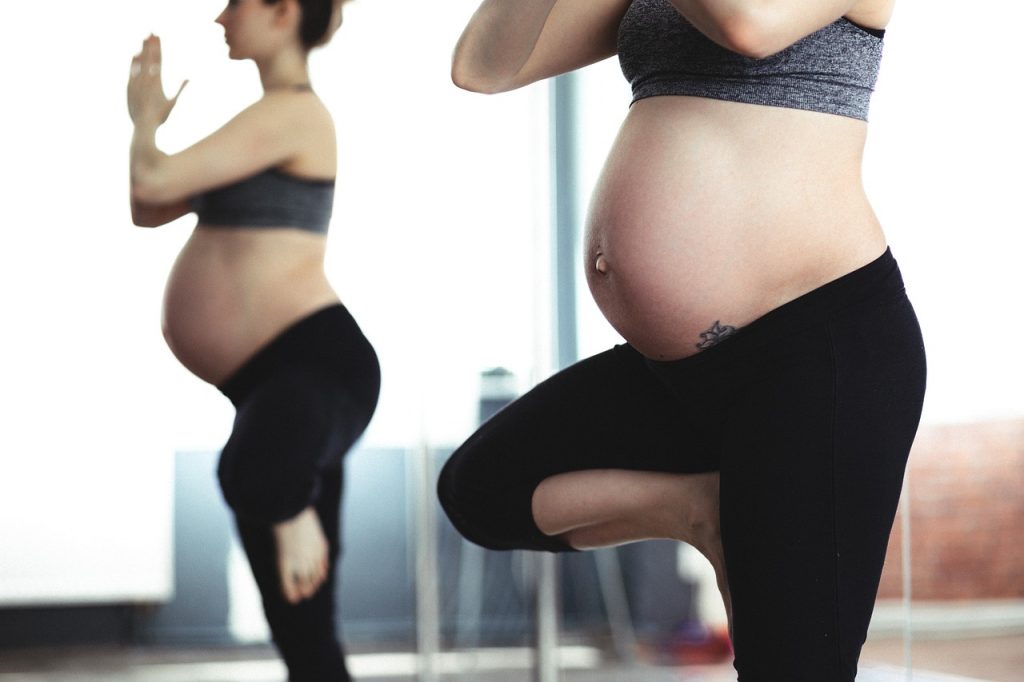 Kobieta w ciąży wykonuje ćwiczenia w stroju sportowym.